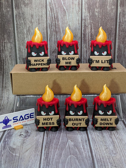 May include: Six black and red candle figurines with yellow flames, each holding a sign. The signs read: WICK HAPPENS, BLOW ME, I'M LIT, HOT MESS, BURNT OUT, and MELT DOWN. A white sign with the text SAGE PRINTS AND DESIGN is visible on the left.